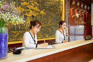 twee vrouwen aan een balie in een restaurant bij Tay Bac Hotel Da Nang in Da Nang