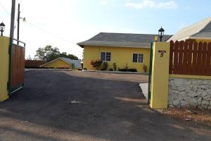 a yellow house with a fence and a driveway at 1 BDR Apt #5 at Ramparts Near Sangster Airport in Montego Bay
