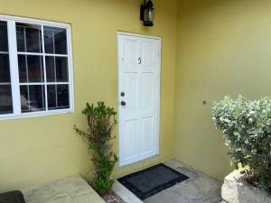 a yellow house with a white door and a window at 1 BDR Apt #5 at Ramparts Near Sangster Airport in Montego Bay