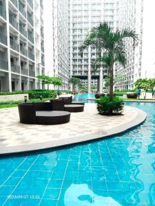 a pool in the middle of a building with palm trees at Shore 2 Residences 1BR Deluxe Room in MOA Complex in Manila