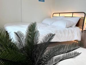 首尔Hongdae Modern House的一间卧室配有一张带白色床单和棕榈树的床。