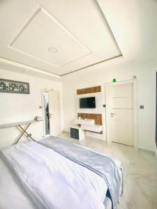 una camera bianca con letto e TV di Thistle Greens Apartment a Ikeja