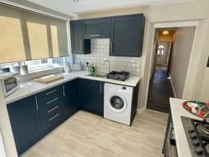 a kitchen with blue cabinets and a washing machine at Edgy 4 Bed Home in Stoke on Trent