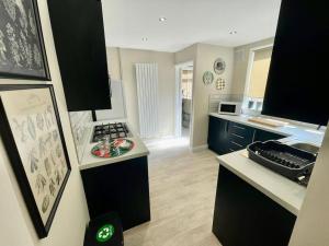 a kitchen with black cabinets and a white counter top at Edgy 4 Bed Home in Stoke on Trent