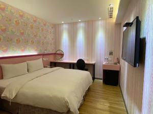 een slaapkamer met een bed, een bureau en een televisie bij 191 Hotel in Taoyuan