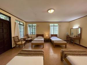 ダバオシティにあるEden Nature Park and Resortのベッド4台、テーブルと椅子が備わる客室です。