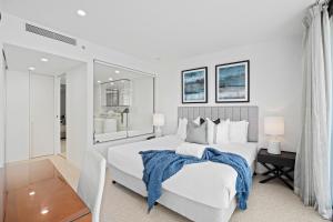 a white bedroom with a large bed and a mirror at Oracle Resort Broadbeach - GCLR in Gold Coast
