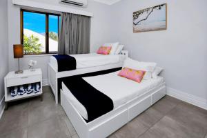 a bedroom with two beds and a window at On the Esplanade 7 in Cairns