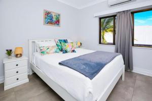 a white bedroom with a bed and a window at On the Esplanade 7 in Cairns