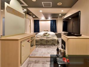 um quarto de hotel com uma televisão e uma cama em Restay DEE (Adult Only) em Tokushima