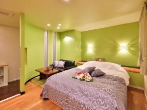 Un dormitorio con paredes verdes y una cama con flores. en Restay DEE (Adult Only) en Tokushima