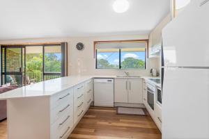 a kitchen with white cabinets and white appliances at Sand Dunes in East Ballina