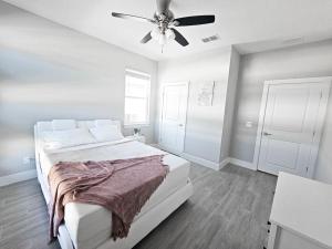 1 dormitorio blanco con 1 cama y ventilador de techo en Spacious Modern 4bd 2ba Home! Close to LEGOLAND, en Winter Haven