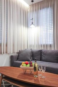 a living room with a table with a bowl of fruit and wine glasses at Cozy Apartment in the Heart of Tel Aviv Sea N' Rent in Tel Aviv