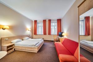 a hotel room with two beds and a red couch at Rija Domus Hotel in Riga