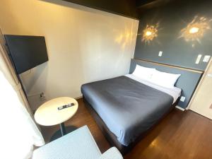 a small room with a bed and a table at BiBi Hotel Conventionbay in Ginowan +8 photos