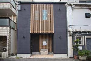 een zwart gebouw met een grote deur met gouden strepen bij Time通天閣2F 近隣Tsutenkaku Nihonbashi in Osaka