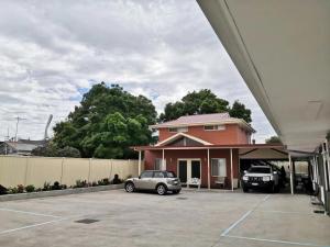 a house with two cars parked in a parking lot at Colonial Lodge Motel in Belmont