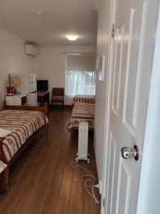 a room with two beds and a door to a room at Colonial Lodge Motel in Belmont