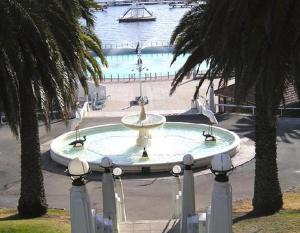 a fountain in the middle of a park with palm trees at Colonial Lodge Motel in Belmont
