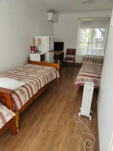 a bedroom with two beds and a table and a refrigerator at Colonial Lodge Motel in Belmont