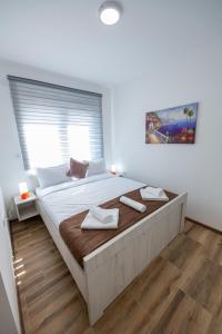 a bedroom with a large bed with two towels on it at M&A Apartmani in Vrdnik