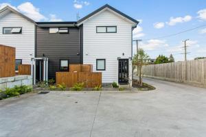a white house with a fence in a driveway at Stunning 2BR in Kelston - WIFI - Carpark in Auckland