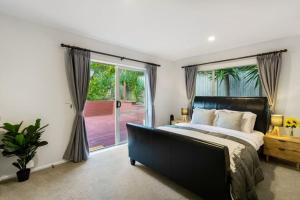 um quarto com uma cama grande e uma porta de vidro deslizante em Albany Bolthole with King Beds and Kitchenette em Auckland