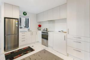 a kitchen with white cabinets and a stainless steel refrigerator at Stunning 2BR in Kelston - WIFI - Carpark in Auckland