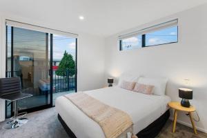 a bedroom with a white bed and a balcony at Stunning 2BR in Kelston - WIFI - Carpark in Auckland