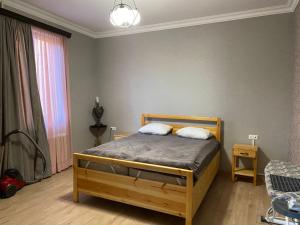 1 dormitorio con 1 cama de madera y 2 almohadas en Family Apartments "IGWT", en Tiflis
