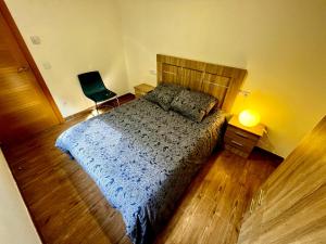 ein Schlafzimmer mit einem Bett, einem Stuhl und einer Lampe in der Unterkunft Lotila Flats L'Infiestu in Infiesto