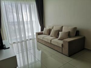 eine Couch in einem Wohnzimmer neben einem Fenster in der Unterkunft Metropol Suite in Bukit Mertajam