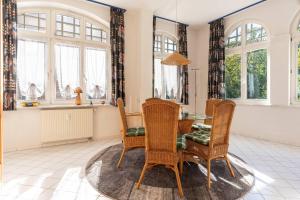 a dining room with a table and chairs and windows at Villa-Sirene-2-Raum-Apartment-ca-54-qm in Binz