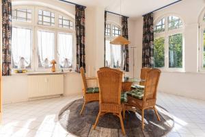 ein Esszimmer mit Tisch und Stühlen und Fenstern in der Unterkunft Villa Sirene 2-Raum Apartment, ca. 54 qm in Binz