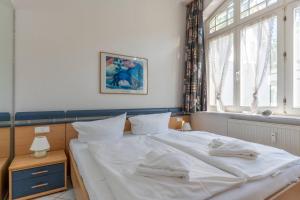 a bedroom with a bed with white sheets and a window at Villa-Sirene-2-Raum-Apartment-ca-54-qm in Binz
