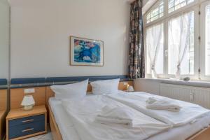 ein Schlafzimmer mit einem Bett mit weißen Laken und einem Fenster in der Unterkunft Villa Sirene 2-Raum Apartment, ca. 54 qm in Binz