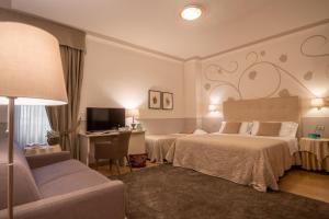 a hotel room with two beds and a desk at Hotel Ambasciatori in Brescia