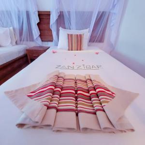 a bed with a blanket on top of it at Zanzibar Bahari Villas in Matemwe