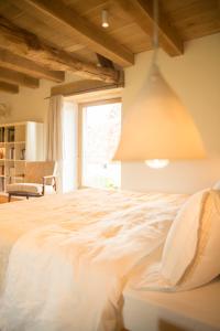 a bedroom with a large white bed with a window at La Queurie in La Courbe