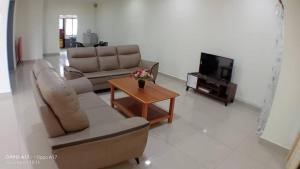 uma sala de estar com um sofá e uma televisão em Anggerik Heights Homestay em Bentong