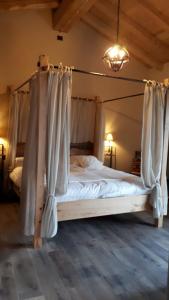 Agriturismo La Pina في Tarzo: غرفة نوم مع سرير مظلة مع ستائر بيضاء