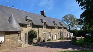 an old stone building with a roof and a driveway at LE MONTESSER in Villebaudon