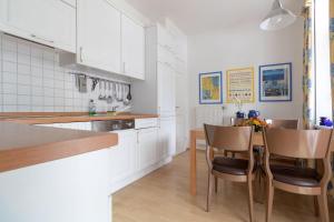 ビンツにあるVilla Eden Binz Typ 2 / Apartment 3の白いキャビネット、テーブルと椅子付きのキッチンが備わります。