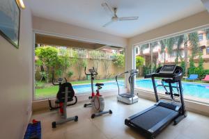 a gym with three exercise bikes and a swimming pool at Veeraas Calangute - 2BHK Apartment with Pool in Marmagao