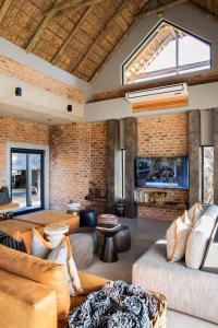 ein Wohnzimmer mit 2 Sofas und einer Ziegelwand in der Unterkunft NAKO Safari Lodge in Dinokeng Game Reserve