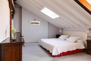 ein Schlafzimmer mit einem weißen Bett und einem Dachfenster in der Unterkunft ático vistas centro 3min playaparking y wifi free in Laredo