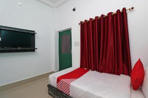 Zimmer mit einem Bett mit einem roten Vorhang und einem TV in der Unterkunft OYO Flagship Fun Friday Guesthouse in Bodh Gaya