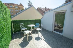 a patio with three chairs and a table and a fence at Central duplex apartment+parking in Novi Sad