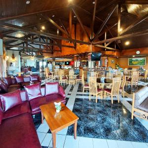 un restaurante con sofás, mesas y sillas en Sangga Buana Resort & Convention Hotel en Pacet